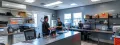 HVAC technicians discussing air conditioning maintenance in a modern service office with tools and equipment for Precision Air, Heating and Cooling.