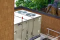 Large commercial HVAC system on a rooftop, featuring dual fans and labeled components, surrounded by greenery and a wooden structure, illustrating Precision Air Heating & Cooling's focus on reliable climate control solutions in Unionville.