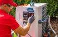 Technician performing maintenance on an outdoor swimming pool heat pump, ensuring optimal HVAC performance for summer cooling in Wawa, PA.