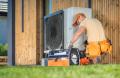 HVAC technician performing heat pump repair service outdoors, surrounded by tools, ensuring efficient heating and cooling for homes in West Chester, PA.