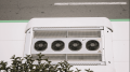Air conditioning unit with multiple fans on a rooftop, surrounded by greenery, relevant to HVAC maintenance and efficiency tips for fall.