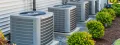 HVAC units installed outside a residential home, showcasing multiple air conditioning systems surrounded by landscaped greenery, emphasizing the importance of regular maintenance for optimal performance.