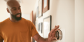 Man adjusting a smart thermostat on the wall, demonstrating home temperature control in an indoor setting related to HVAC efficiency and comfort.