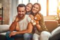 Family enjoying quality time at home, smiling together on a couch, with a child holding a teddy bear, reflecting comfort and warmth in a cozy living space, emphasizing family life and home comfort related to HVAC services.