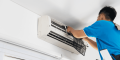 HVAC technician performing maintenance on a wall-mounted air conditioning unit, emphasizing professional HVAC services in Malvern, PA.