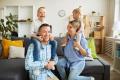 Family enjoying quality time at home, parents smiling with children on their shoulders in a cozy living room setting, emphasizing comfort and family bonding.