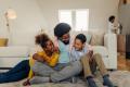 Father playing and tickling his children in a cozy living room, emphasizing family comfort and joy in a home environment, reflecting the importance of HVAC services for year-round home comfort.