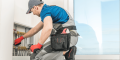 HVAC technician adjusting heating system components, emphasizing professional maintenance for energy efficiency during extreme weather conditions.