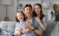Happy father and two children smiling together on a couch, celebrating family moments, emphasizing comfort and joy in a home setting.