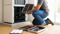 Technician replacing air filter in HVAC unit, tools and maintenance checklist nearby, highlighting HVAC repair and maintenance services.