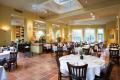 Elegant restaurant interior with tables set for dining, featuring warm colors, natural light, and decorative floral arrangements, emphasizing climate control for guest comfort.