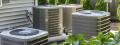 Residential HVAC units installed outside a home, showcasing multiple air conditioning compressors against a backdrop of greenery and siding, relevant to HVAC installation process.