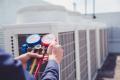 HVAC technician using pressure gauges on air conditioning units for maintenance and repair services in Chadds Ford.