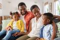 Happy African American family portrait on a couch in West Chester, PA. Mother, father, daughter, and son smiling and spending quality time together.