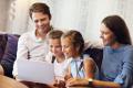 Happy family enjoying quality time together in a hotel room, engaging with a laptop, emphasizing comfort and relaxation.