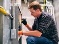 Expert performing a Furnace Maintenance and Inspection with a flashlight. Safety glasses are on, and work gloves are on for protection.