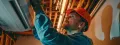 HVAC technician wearing a hard hat and gloves installing a cooling system in a residential setting, emphasizing professional service for Southeastern Pennsylvania homeowners.