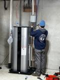 Technician installing a heat pump water heater in a residential basement, showcasing energy-efficient technology for water heating.