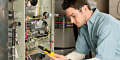 Technician inspecting a heating system with a multimeter, emphasizing HVAC maintenance and repair services.