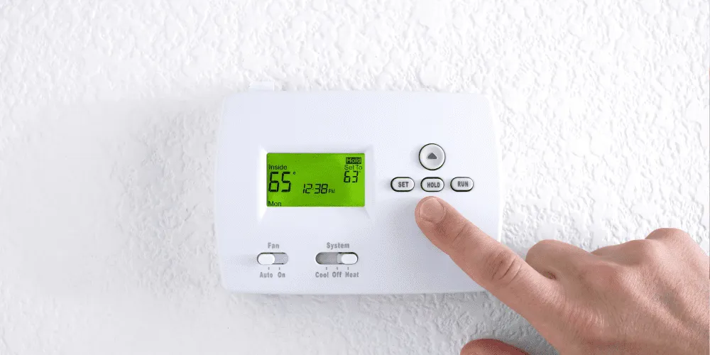 Smart Thermostat for Energy Savings: Finger pressing the HOLD button to maintain a constant temperature in West Chester, PA.