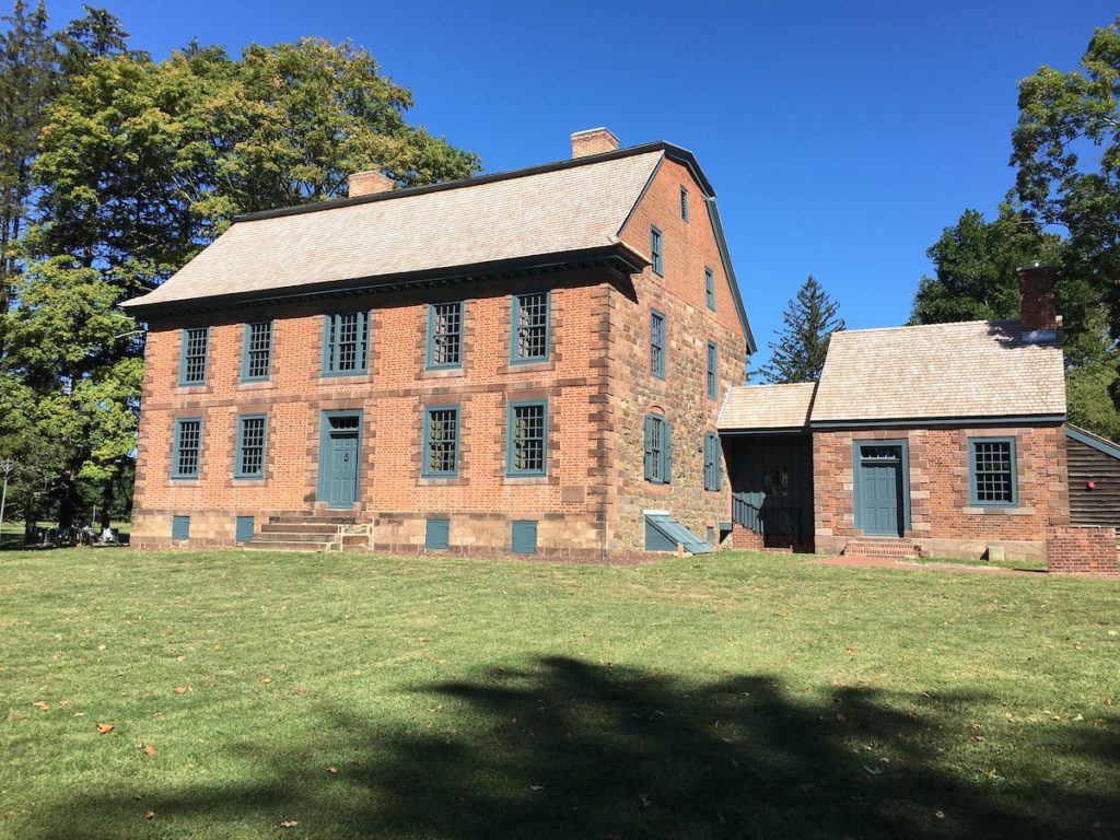 Dey Mansion, historic landmark in Wayne, showcasing brick architecture and green accents, surrounded by trees and lawn.