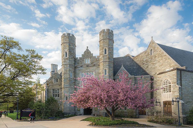 Historic stone building with towers and a blooming cherry tree in West Chester, PA, under a partly cloudy sky. Spring is in the air!