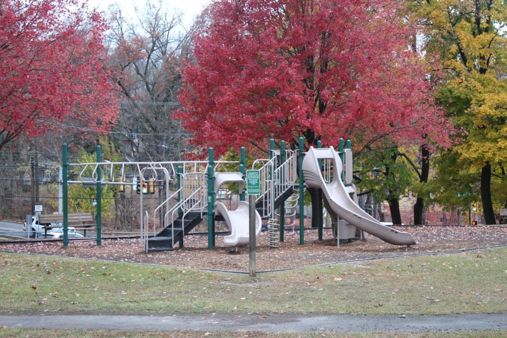 Playground equipment with slides and climbing structures surrounded by colorful autumn trees in Paoli, emphasizing family-friendly outdoor spaces.