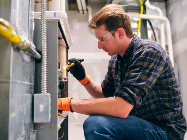 Expert performing a Furnace Maintenance and Inspection with a flashlight. Safety glasses are on, and work gloves are on for protection.