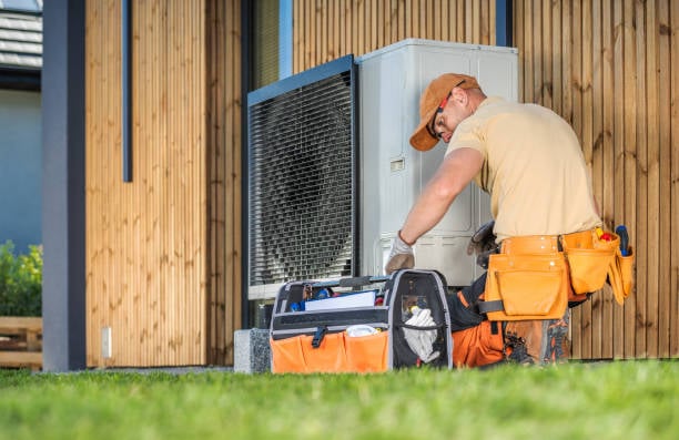 HVAC technician performing heat pump repair service outdoors, surrounded by tools, ensuring efficient heating and cooling for homes in West Chester, PA.