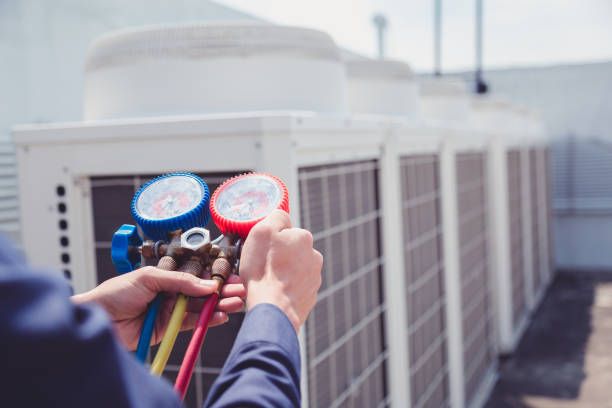HVAC technician using pressure gauges on air conditioning units for maintenance and repair services in Chadds Ford.