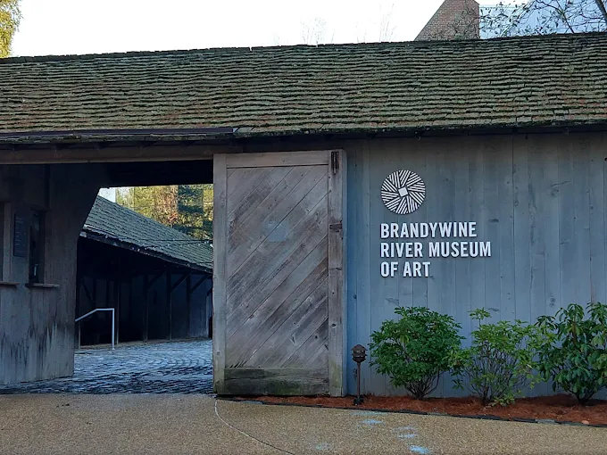Brandywine River Museum of Art entrance featuring wooden door and signage, surrounded by greenery, located in Chadds Ford, PA, highlighting local cultural landmarks.