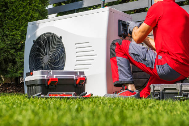 Heat pump maintenance in progress. Technician services outdoor HVAC unit with tools. Ensuring efficient home heating and cooling systems.