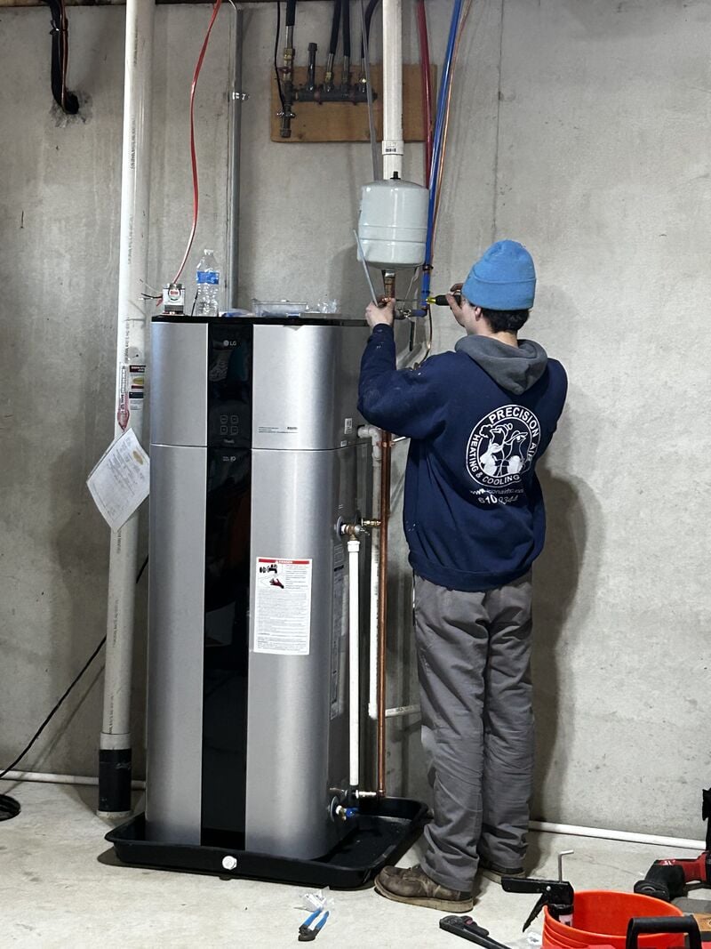Precision Air technician connecting the water lines and expansion tank on a newly installed water heater in a West Chester basement
