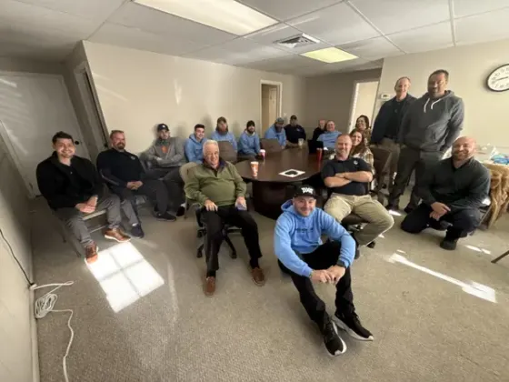 The Precision Air team gathered around the table at a company meeting