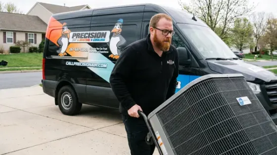 Precision Air technician unloading an AC coil from the service van on a hand truck